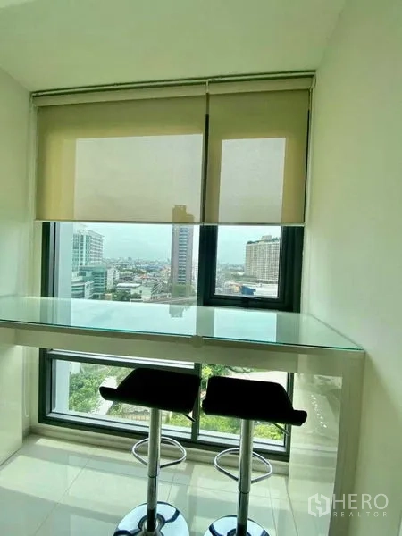 Condominium for rent in Khlong Toei, Bangkok - Window-side breakfast bar with two stools overlooking the Bangkok cityscape.