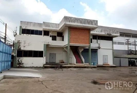 Factory for sale in Bang Phli, Samut Prakan - Side view of factory building with external staircase, roller shutters and service doors.