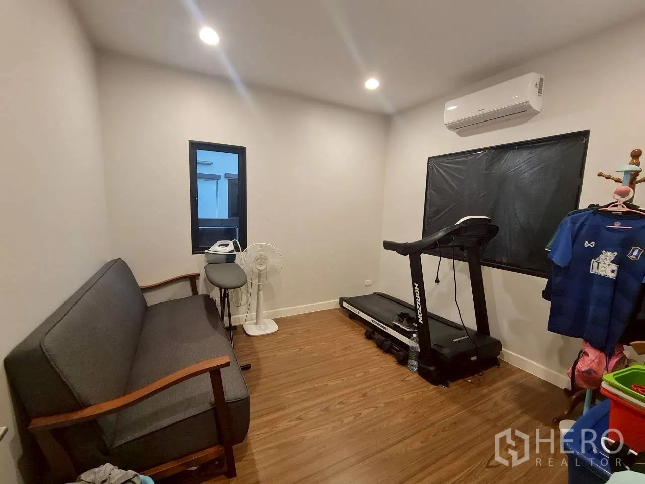Detached House for rent or sale in Lam Luk Ka, Pathum Thani - Multi-purpose room arranged as a home gym with treadmill, sofa and air conditioner.