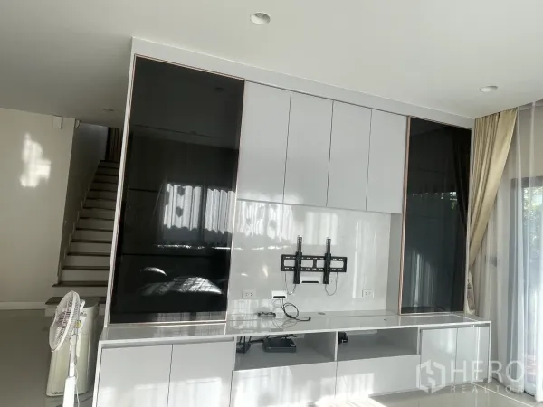 Detached House for rent or sale in Lam Luk Ka, Pathum Thani - Built-in media cabinet with display shelves opposite the staircase and sliding doors to the garden.