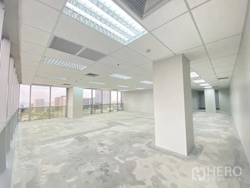 Office Space for rent in Chatuchak, Bangkok - Open workspace with structural columns, ceiling air vents and wall-to-wall windows on two sides.