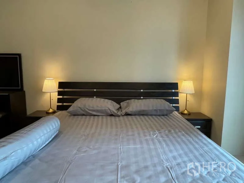 Apartment for rent in Khlong Toei, Bangkok - Close-up of king-size bed with bedside tables and warm lamps.