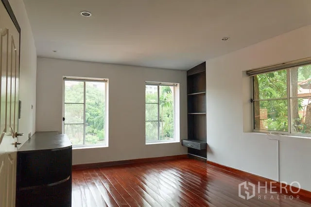 Detached House for rent in Watthana, Bangkok - Bright room with three windows, built-in storage and garden views.