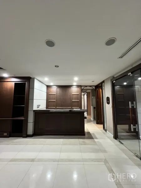 Office Space for rent in Watthana, Bangkok - Front view of a dark wood reception desk under ceiling lights.