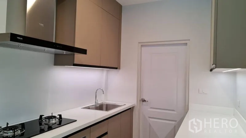 Detached House for rent in Samut Prakan - Fitted galley kitchen with gas hob, range hood and stainless-steel sink.