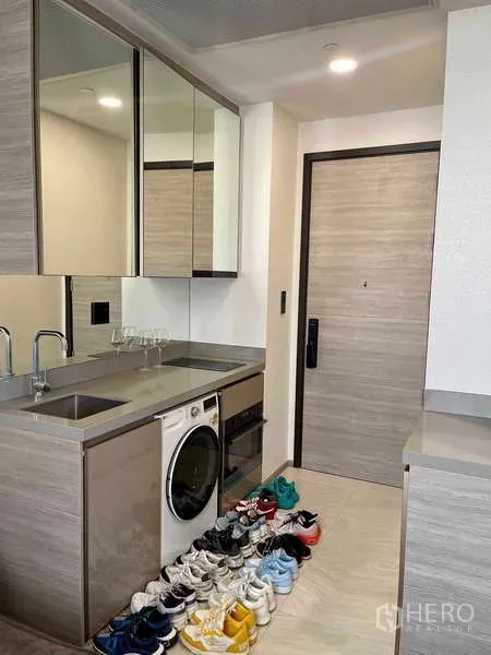 Condominium for rent - Compact pantry with sink, mirrored cabinets and front-load washer near the entrance.