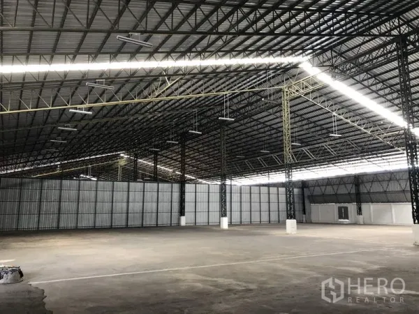 Warehouse for rent in Mueang Pathum Thani, Pathum Thani - Open industrial warehouse with metal sheet walls, bright linear lighting and expansive floor area for storage and logistics.