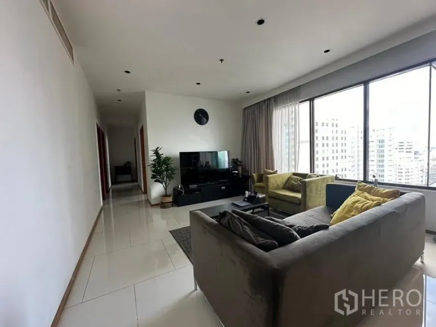 Condominium for sale in Khlong Toei, Bangkok - Bright living room in Bangkok condo with large windows, city view, TV unit and sectional sofa.