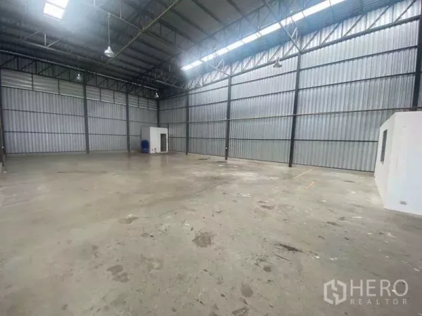 Warehouse for rent in Bang Phli, Samut Prakan - Spacious warehouse interior with a high steel truss roof, skylights, and polished concrete floor.