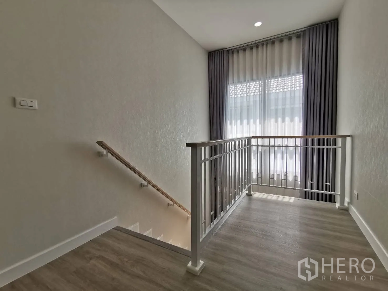 Detached House for rent in Bang Phli, Samut Prakan - Bright stair landing with white railing and a tall curtained window.