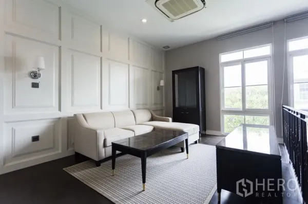 Detached House for rent in Mueang Samut Prakan, Samut Prakan - Upstairs family lounge with sofa, paneled feature walls and ample natural light from tall windows.