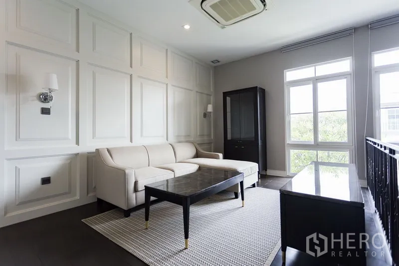 Detached House for rent in Mueang Samut Prakan, Samut Prakan - Upstairs family lounge with sofa, paneled feature walls and ample natural light from tall windows.