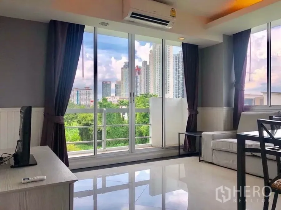 Condominium for rent in Khlong Toei, Bangkok - Living room opening to a balcony with skyline and park views near On Nut.