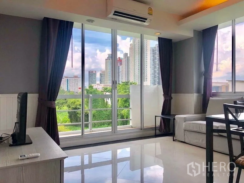Condominium for rent in Khlong Toei, Bangkok - Living room opening to a balcony with skyline and park views near On Nut.