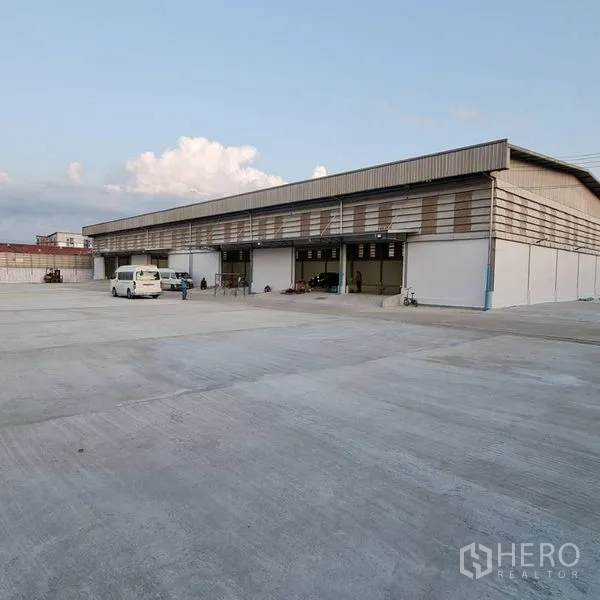 Warehouse for rent in Prawet, Bangkok - Long warehouse facade with multiple loading bays opening to a large truck yard.