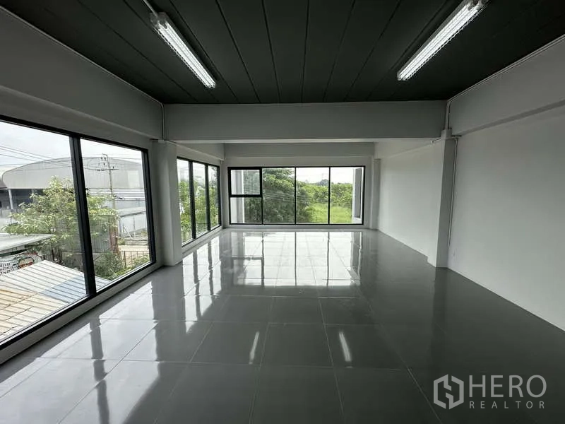 工厂 出租或出售在Bang Bua Thong, Nonthaburi - 明亮的办公楼层，全景玻璃俯瞰树景。