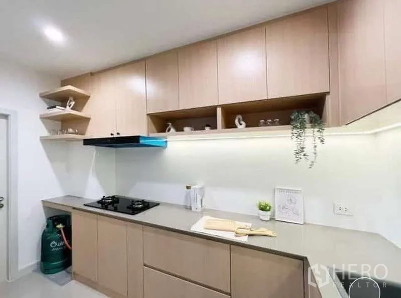 Townhouse for rent or sale in Saphan Sung, Bangkok - Modern kitchen with light wood cabinetry, gas hob, range hood and solid-surface countertop.