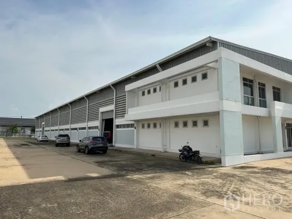 Factory for rent in Phra Nakhon Si Ayutthaya - Side view of factory showing loading bay door, parking area, and attached two-storey office block.