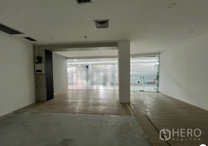 Retail Space for rent - Deep interior facing the glass entrance with mixed wood and concrete flooring, ideal for customization.