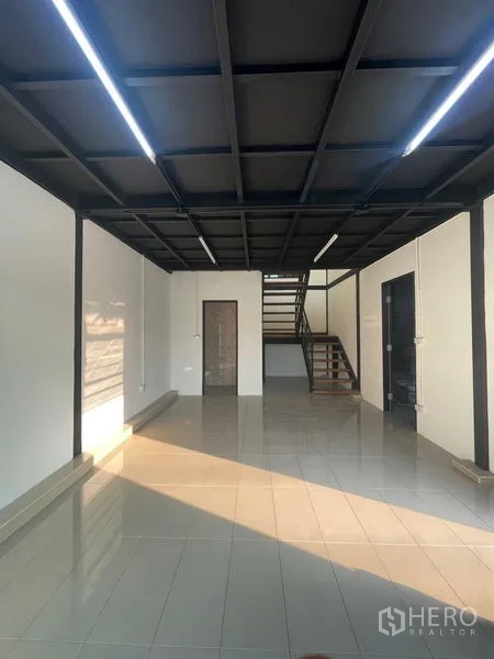 货栈 出租在Bang Kapi, Bangkok - 一层办公区，瓷砖地面与黑色格栅天花，连接楼梯