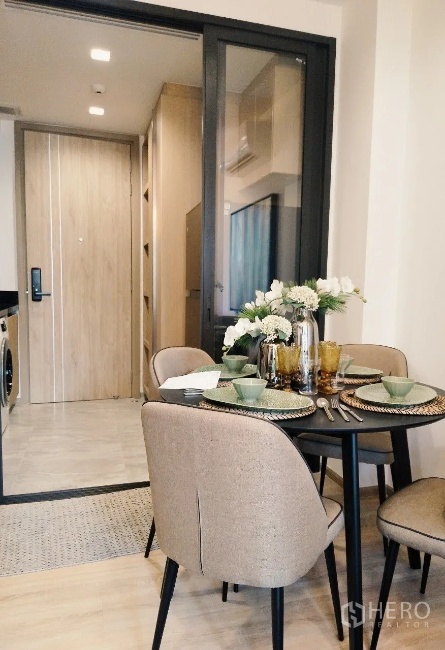 Condominium for rent in Watthana, Bangkok - Dining table set for four next to a sliding glass partition to the kitchen.