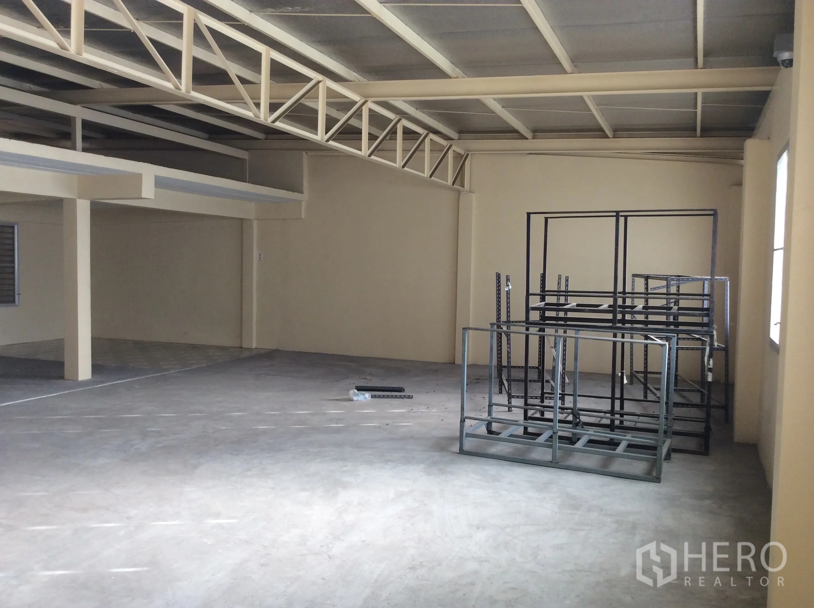 Factory for rent in Thung Khru, Bangkok - Open area beneath steel beams with modular storage racks on concrete floor.