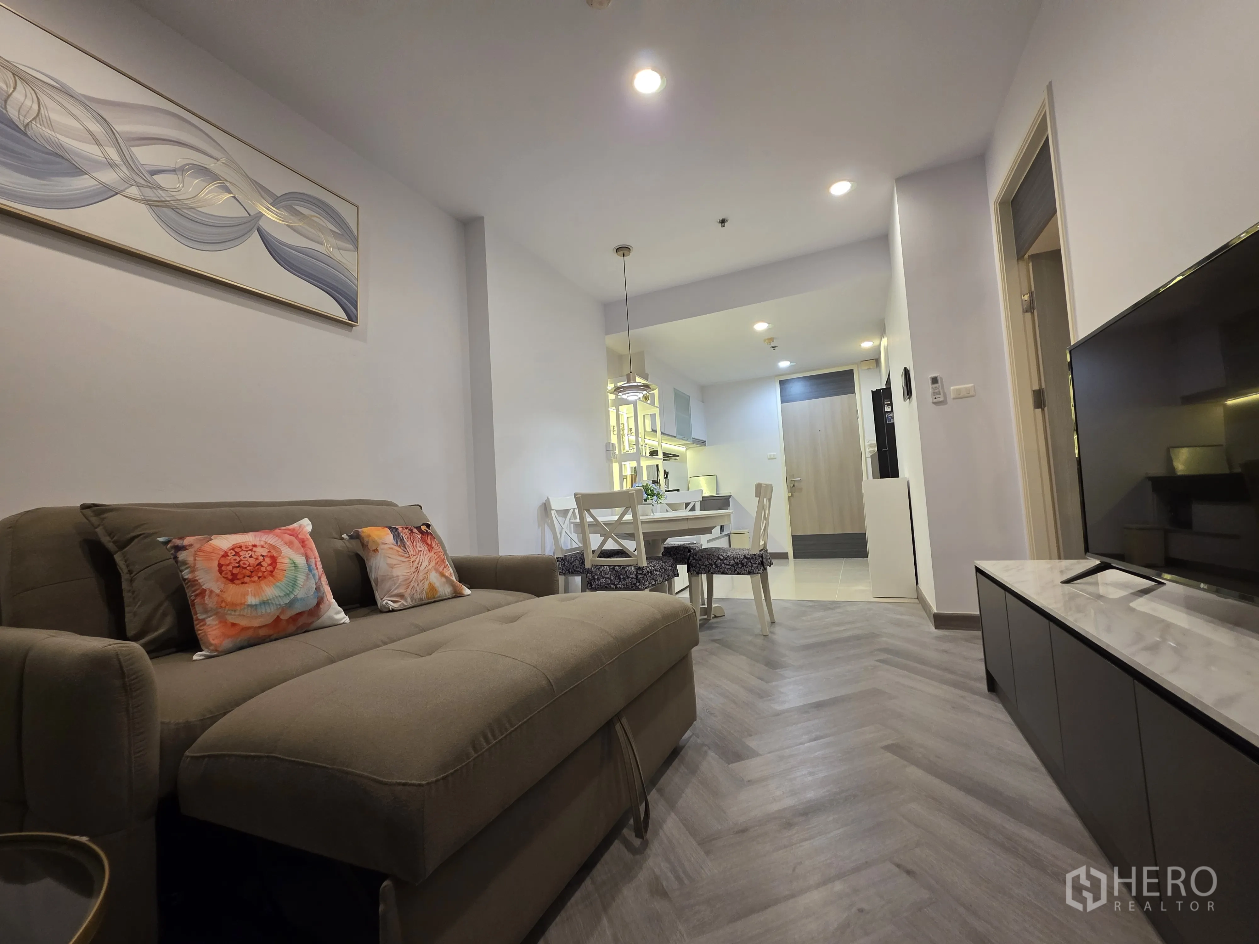 Condominium for rent in Bang Kapi, Bangkok - Dining and living zone with TV, full-length curtains, and accent shelving.