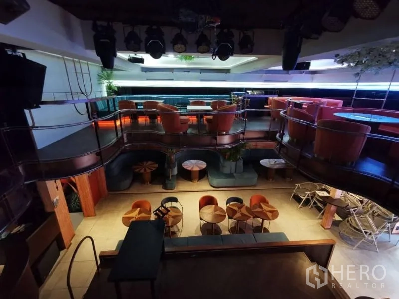 Retail Space for rent - View from stage of a two-level dining hall with curved mezzanine, spotlights, and clustered tables.