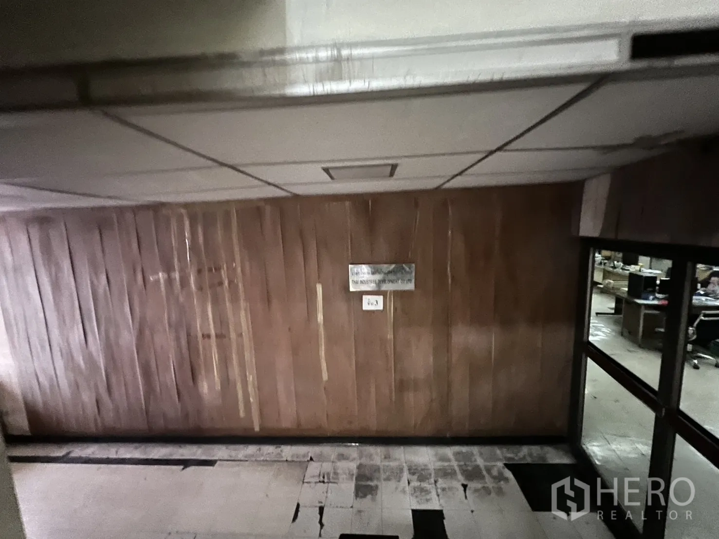 Shophouse for rent - Hallway with wood wall panels and aged tiled floor outside office.