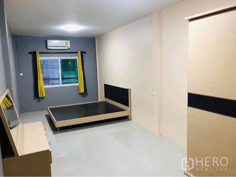 Townhouse for rent or sale in Huai Khwang, Bangkok - Air-conditioned bedroom with bedframe, wardrobe and a window with curtains.