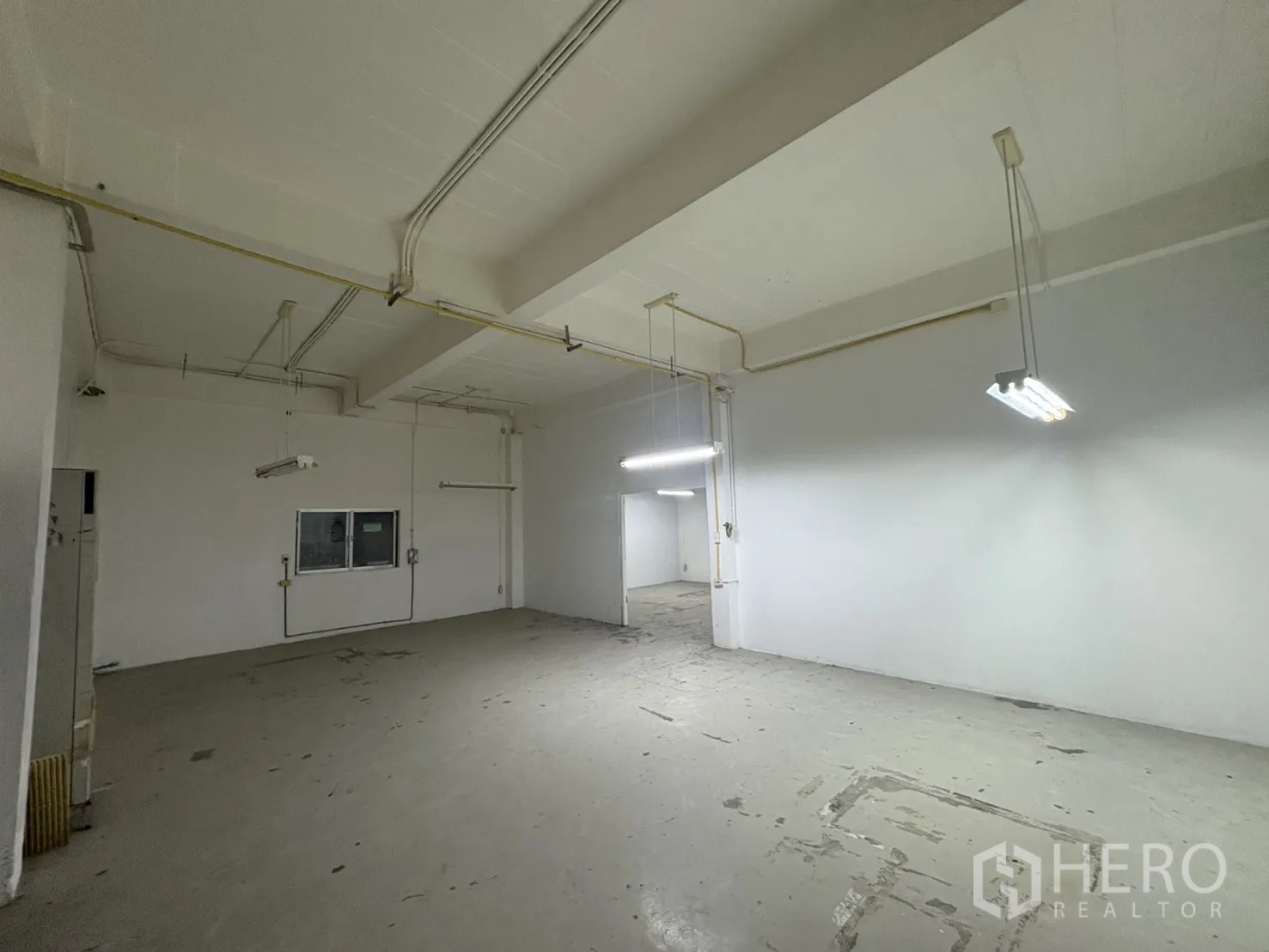 Warehouse for rent in Bang Phli, Samut Prakan - High-ceiling hall with exposed pipes and electrical conduits.