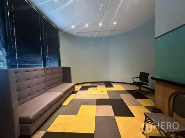 Office Space for rent - Curved lounge and meeting area with long tufted banquette, patterned carpet tiles and blackout blinds.