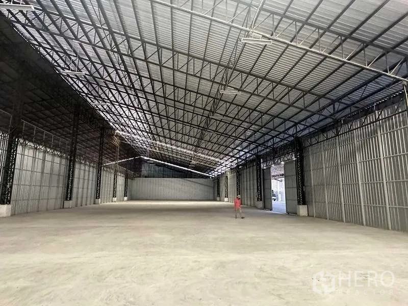 Warehouse for rent in Mueang Pathum Thani, Pathum Thani - Open industrial hall with metal cladding walls, high clearance, and multiple access points.