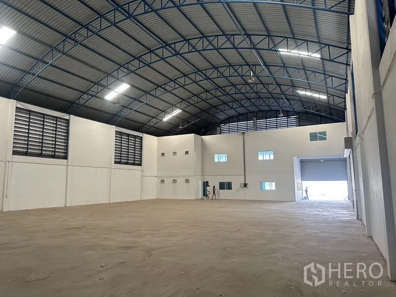 工厂 出租在Bang Bo, Samut Prakan - 开阔仓库地面，拱形钢梁屋顶与墙体百叶通风口。