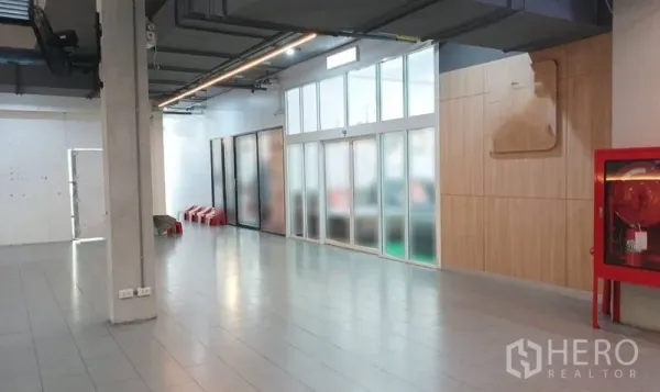 Retail Space for rent in Watthana, Bangkok - Spacious corridor with tiled floor, frosted-glass storefront, wood panel wall and a red fire hose cabinet.