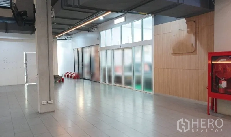 Retail Space for rent in Watthana, Bangkok - Spacious corridor with tiled floor, frosted-glass storefront, wood panel wall and a red fire hose cabinet.