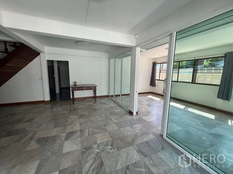 Detached House for rent in Bang Na, Bangkok - Open-plan living area with glass partitions and access to the staircase.