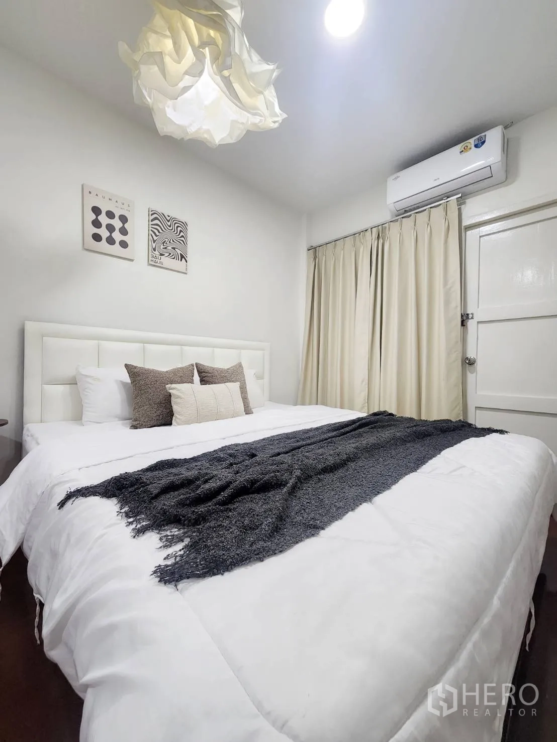 Detached House for rent in Huai Khwang, Bangkok - Cozy bedroom with white bed, pendant light, air conditioner, and beige curtains.