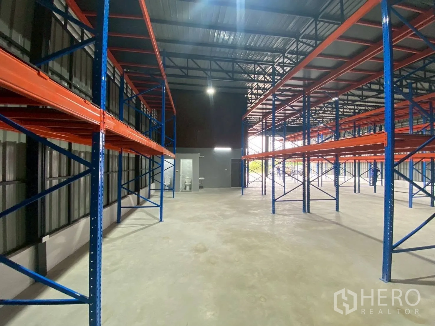 Warehouse for rent in Lam Luk Ka, Pathum Thani - Warehouse interior with high roof, pallet racking, and a restroom area at the rear.
