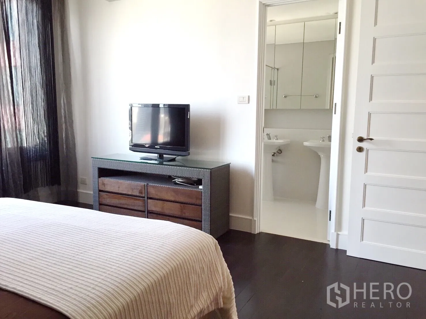 Condominium for rent in Khlong Toei, Bangkok - Bedroom view to TV console and ensuite bathroom with twin pedestal sinks