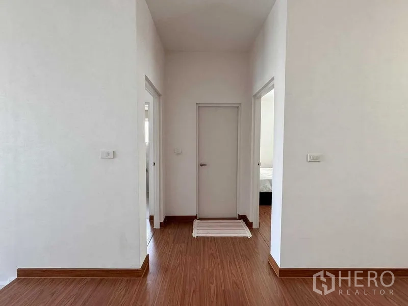 Detached House for rent or sale in Bang Khen, Bangkok - Upstairs landing with three doors, white walls and wood-look flooring.