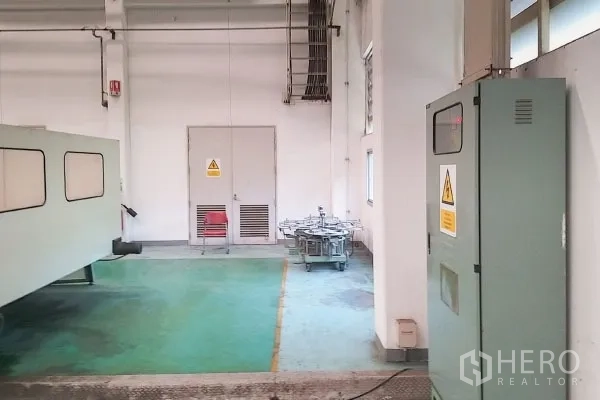 Factory for sale in Rayong - Workshop corner with electrical cabinets, warning signage and green epoxy flooring.