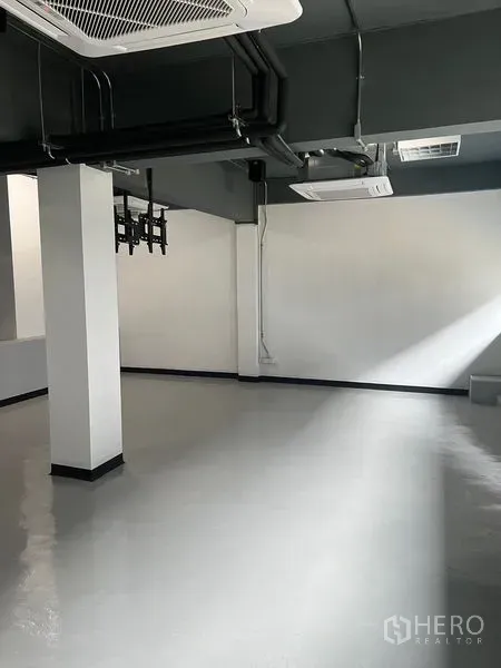 Retail Space for rent in Watthana, Bangkok - Bright corner of empty retail space with epoxy flooring, white walls and exposed piping.