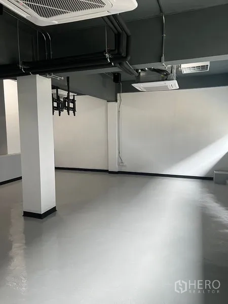 Retail Space for rent in Watthana, Bangkok - Bright corner of empty retail space with epoxy flooring, white walls and exposed piping.
