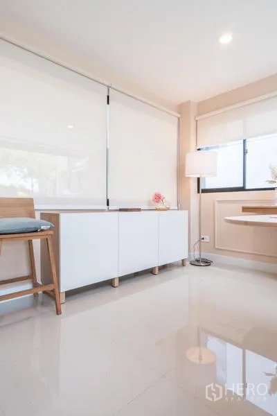 Townhouse for rent or sale in Suan Luang, Bangkok - Dining corner with white sideboard, floor lamp, and glossy tiled floor.