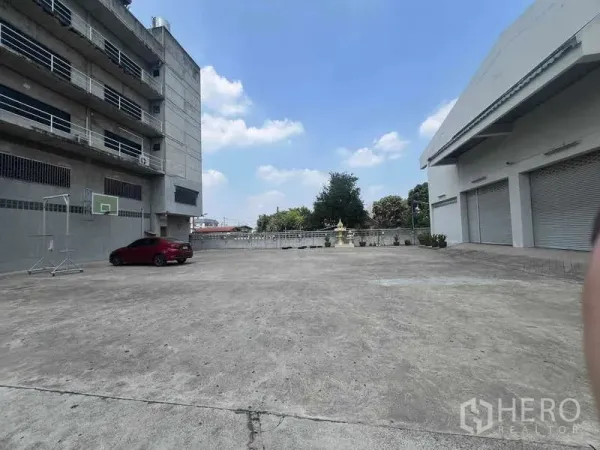货栈 出租在Lam Luk Ka, Pathum Thani - 仓库前大型混凝土院子，带多扇卷闸装卸口和停车位