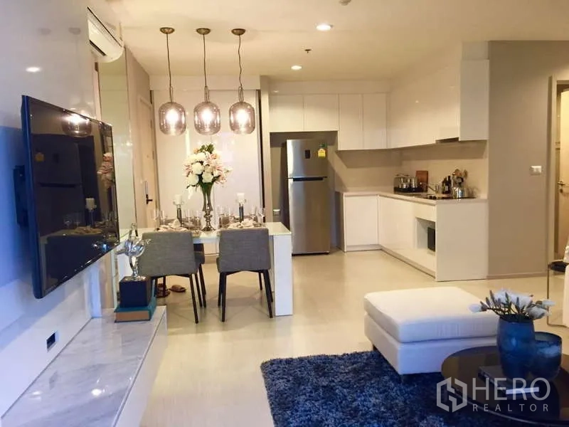 Condominium for rent in Khlong Toei, Bangkok - Open-plan living, dining and white kitchen with full-height cabinets and fridge.