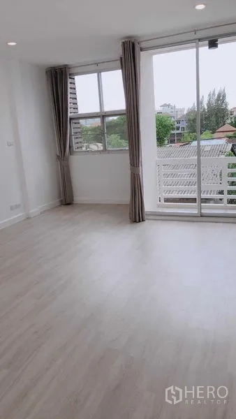 Home Office for rent in Wang Thonglang, Bangkok - Bright upper-floor room with light wood flooring, sliding glass door to a balcony and green city views.