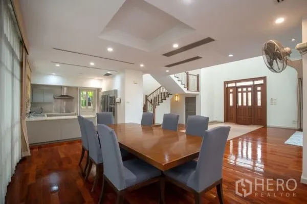 Detached House for rent in Watthana, Bangkok - Dining area for eight adjoining an open-plan layout with kitchen and staircase.