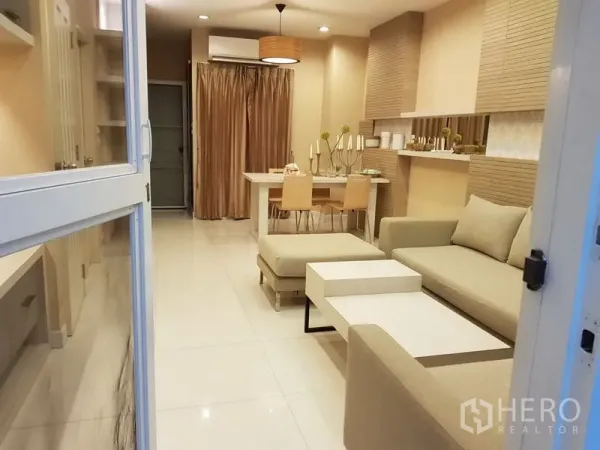 Townhouse for rent in Phra Khanong, Bangkok - Open-plan living and dining area with neutral decor, sectional sofa and white tile floors.